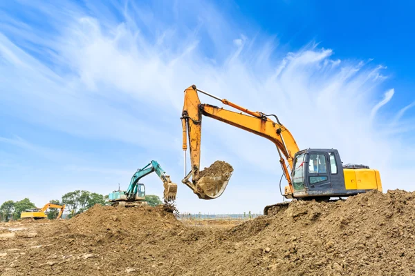 Excavators performing excavation work on a construction site, preparing land for foundations and metal building installations.