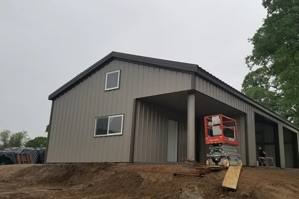 Metal building under construction in Woodland, CA, featuring a modern design, scaffolding, and surrounding earthworks, representing Ibarra Construction's services for agricultural and commercial structures.