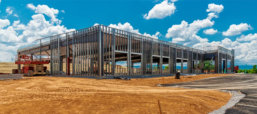 Metal building under construction with steel framing, showcasing Ibarra Construction's commercial construction services in Woodland, CA, against a vibrant sky.