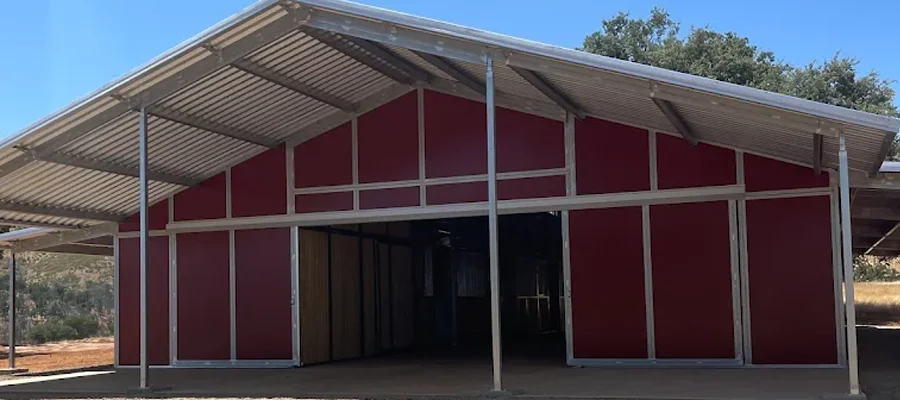 Metal building structure in Davis, CA, showcasing a red exterior with a gabled roof, designed for agricultural or commercial use, representing Ibarra Construction's expertise in durable metal construction.