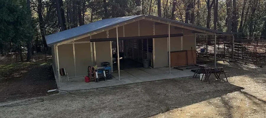 Metal building structure with a sloped roof, featuring a concrete foundation, surrounded by trees, designed for equipment storage or livestock shelter in Dixon, CA.