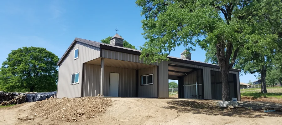 Custom-built steel barn structure with modern design, surrounded by trees and open land, showcasing Ibarra Construction's barn construction services in Woodland, CA.
