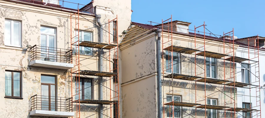 Building renovation in progress with scaffolding, showing exterior work on walls and balconies.