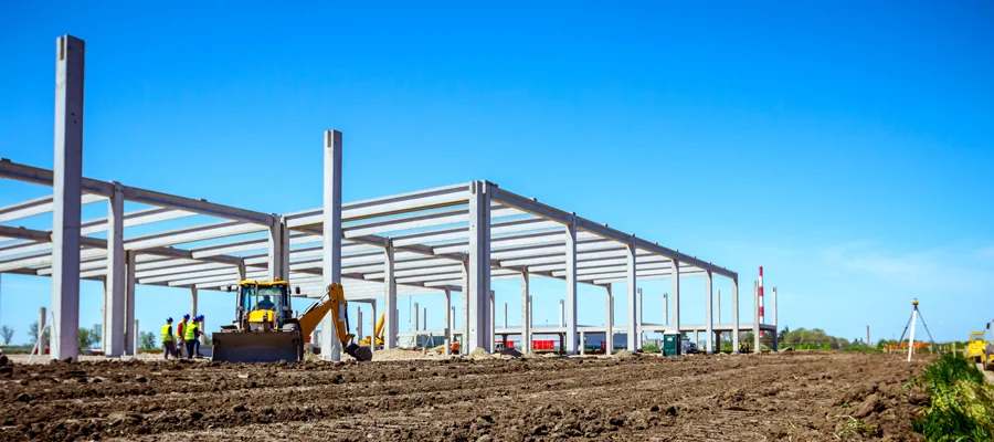 Construction site in Woodland, CA, featuring a partially built steel structure, heavy machinery, and workers engaged in site development and foundation work.