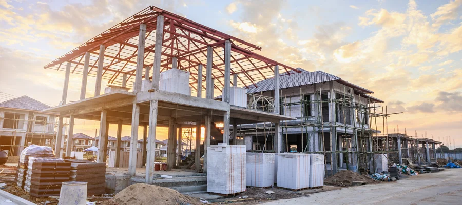 Residential construction site with steel framework and concrete foundations, showcasing ongoing metal building projects in a suburban setting, emphasizing Ibarra Construction's focus on durable structures.