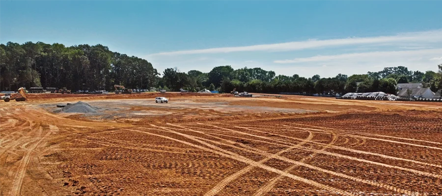 Site preparation area with graded earth, showing tire tracks, machinery, and a clear blue sky, illustrating Ibarra Construction's land leveling and grading services in Woodland, CA.