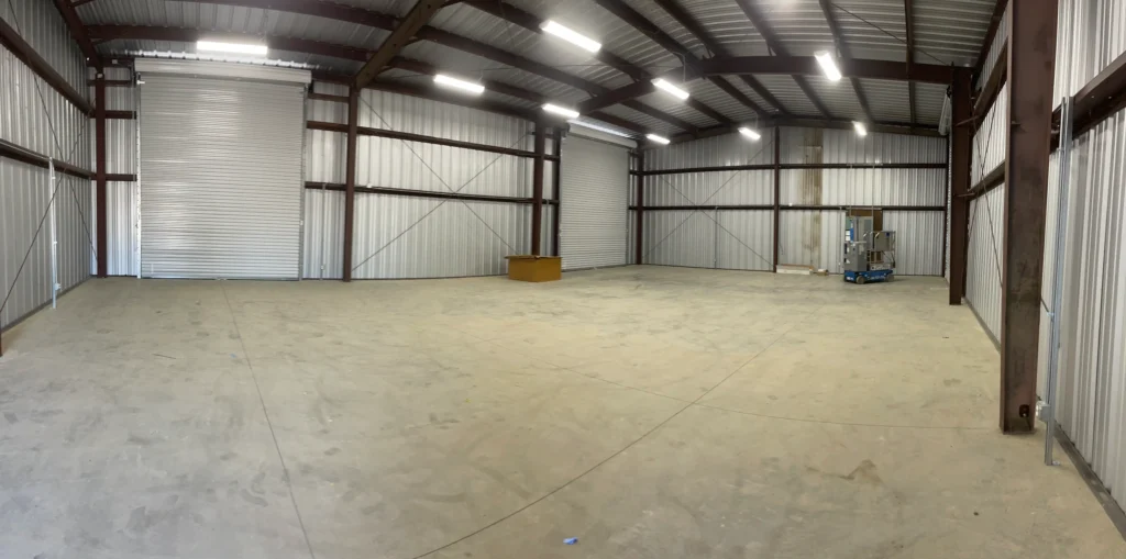 Commercial steel riding arena interior with spacious layout, concrete floor, and metallic structure, showcasing Ibarra Construction's craftsmanship in Esparto, CA.