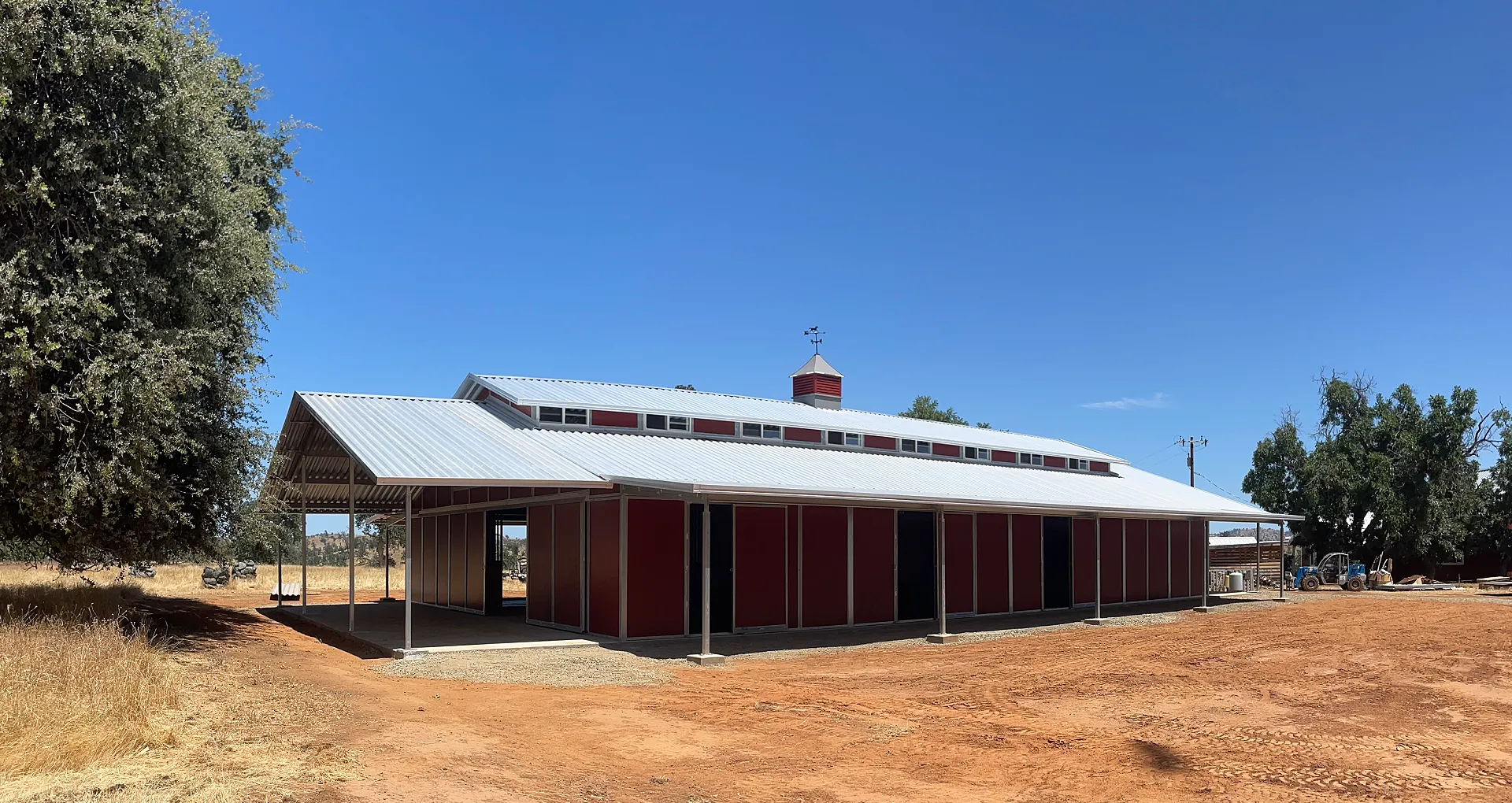 Commercial horse barn with insulated interior, steel framing, and concrete foundation in Elk Creek, CA, featuring a metal roof and surrounding agricultural landscape.