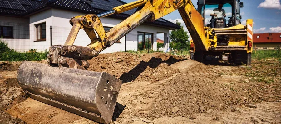 Excavator preparing site for foundation work on a construction project, highlighting earthmoving and grading processes essential for metal building construction.