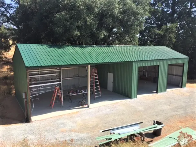 Completed cold-formed steel building with multiple garage doors and green metal roofing.