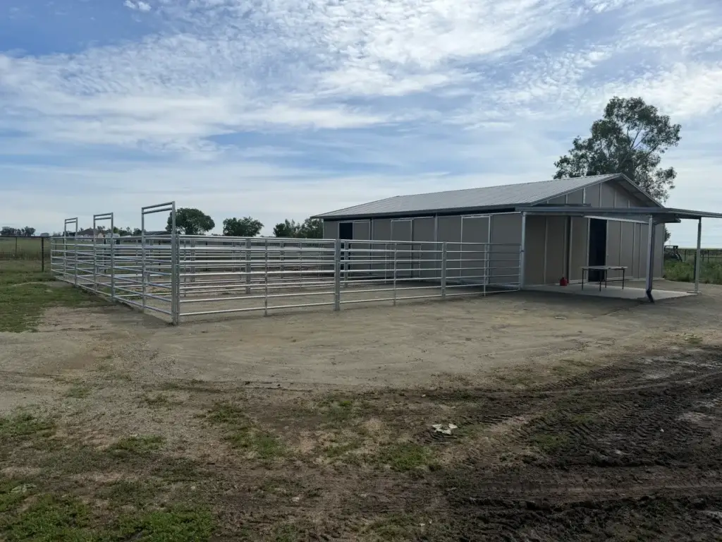 Metal horse barn construction with concrete foundation and metal fencing.
